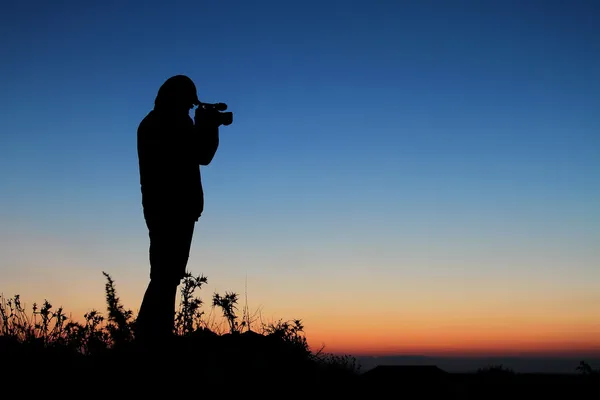 Silhueta de homem com câmera de vídeo ao pôr do sol — Fotografia de Stock