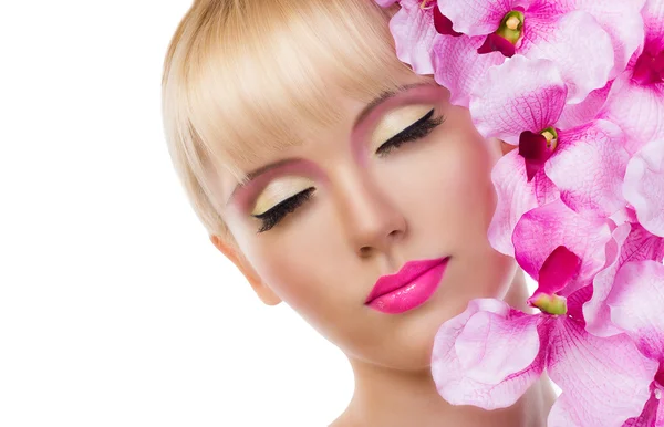 Prachtige blond meisje met bloemen en roze make-up — Stockfoto