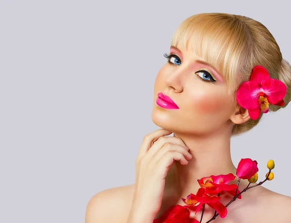 Schöne blonde Mädchen mit Blume auf grauem Hintergrund — Stockfoto