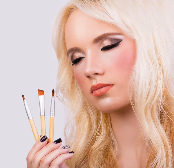 Beautiful blonde girl with makeup brushes — Stock Photo, Image