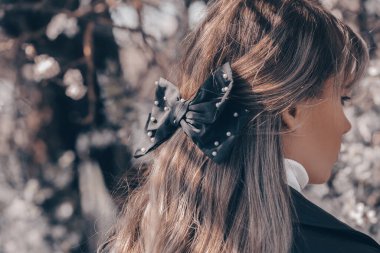 Uzun dalgalı saçlı, siyah kurdeleli güzel bir genç kadının portresi. Arka plan.