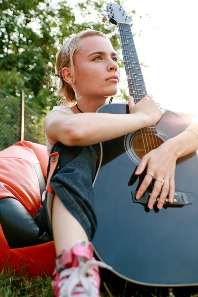 Girl holding a guitar on the grass — Stock Photo, Image