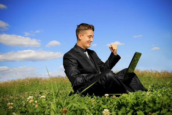 Uomo d'affari in mezzo al campo sul computer portatile — Foto Stock