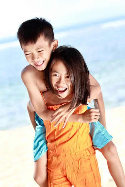 Menina feliz carregando seu irmão — Fotografia de Stock