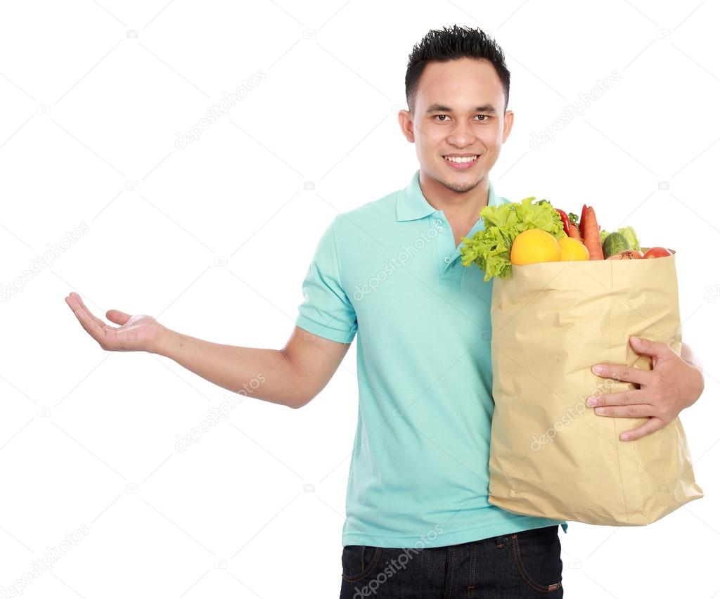 man holding shopping bag full of groceries presenting