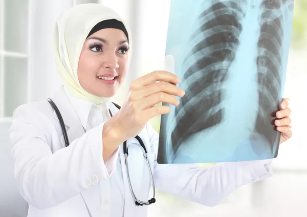Улыбающийся азиатский врач смотрит на рентген — стоковое фото