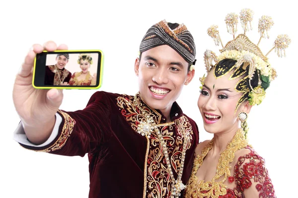 Happy traditional java wedding couple with mobile phone — Stock Photo, Image