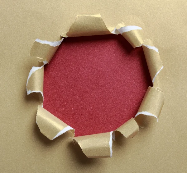 Hole ripped in gold paper — Stock Photo, Image