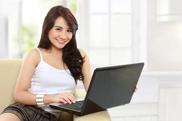 Jovem mulher asiática sentado no sofá usando um laptop — Fotografia de Stock