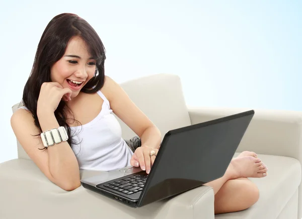 Mujer joven sentada en un sofá usando una computadora portátil — Foto de Stock