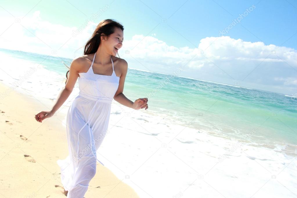 Young happy woman running on the beach