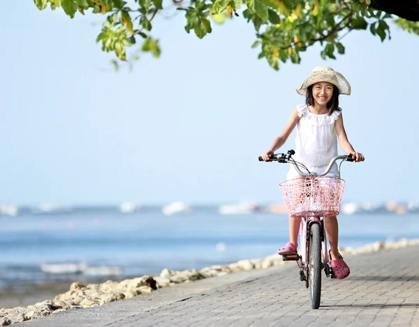 Menina litte atraente feliz vestindo um chapéu andar de bicicleta ao ar livre — Fotografia de Stock