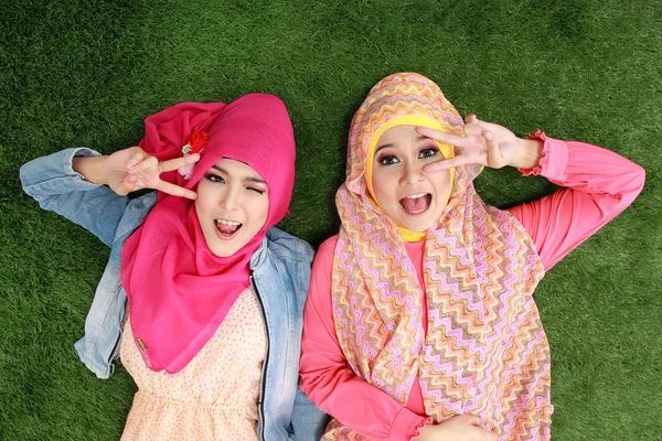 Two muslim woman lying on grass — Stock Photo, Image