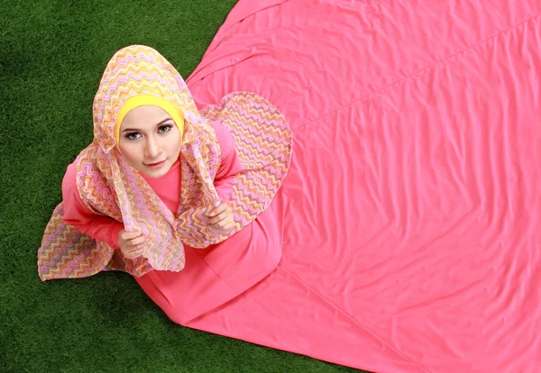Chica musulmana joven sentada en la hierba — Foto de Stock