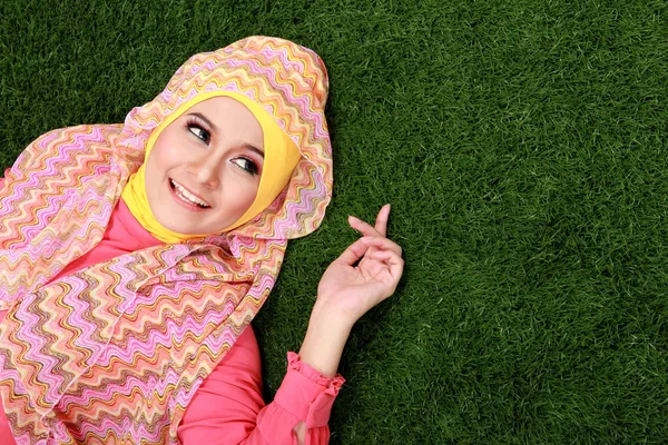 Chica musulmana joven acostada en la hierba — Foto de Stock