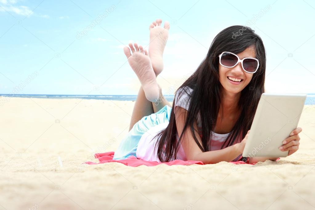woman uses touchpad tablet on the beach