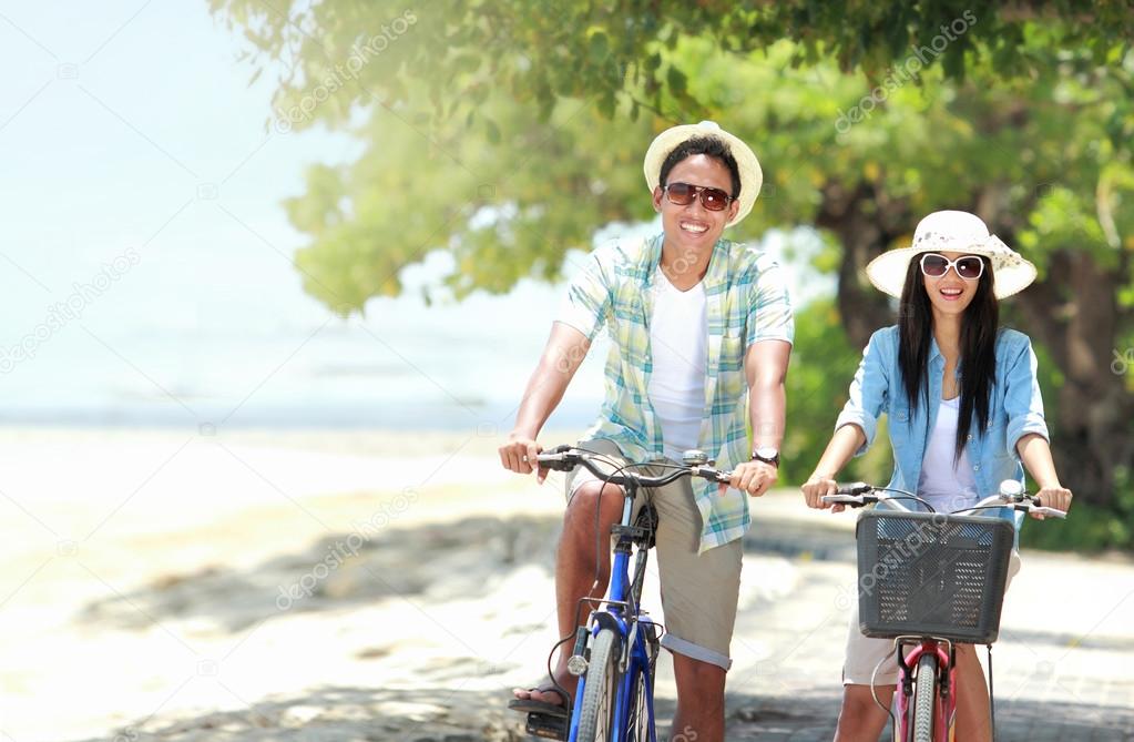 couple having fun riding bicycle at the beach