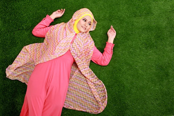 草の上に横たわるヒジャーブを着ている若いイスラム教徒の女性 — ストック写真