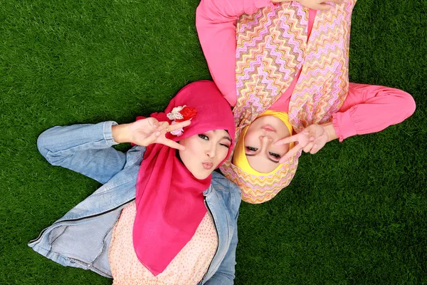 Two beautiful happy muslim woman smiling lying on grass — Stock Photo, Image