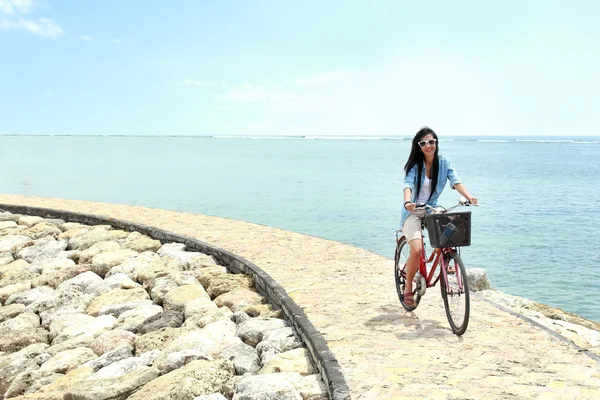 Mujer divirtiéndose montando bicicleta en la playa — Foto de Stock