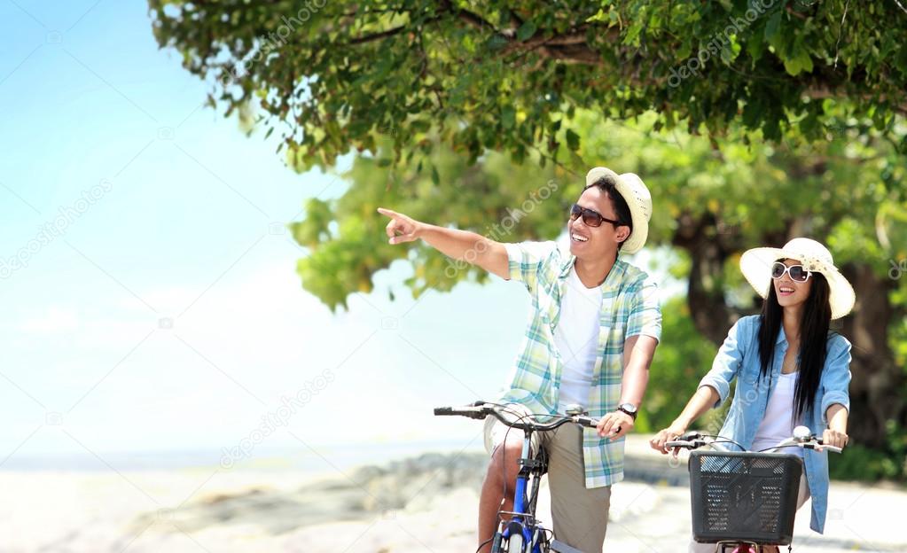 Man and woman having fun outdoor riding bicycle together