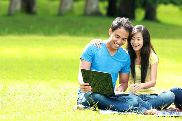 Šťastný mladý pár přes notebook venkovní — Stock fotografie
