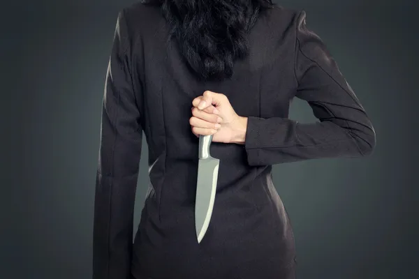 Geschäftsfrau hält Messer hinter seinem Rücken — Stockfoto