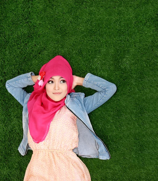 Copyspace を見上げている草の上に横たわるヒジャーブを着ている少女 — ストック写真