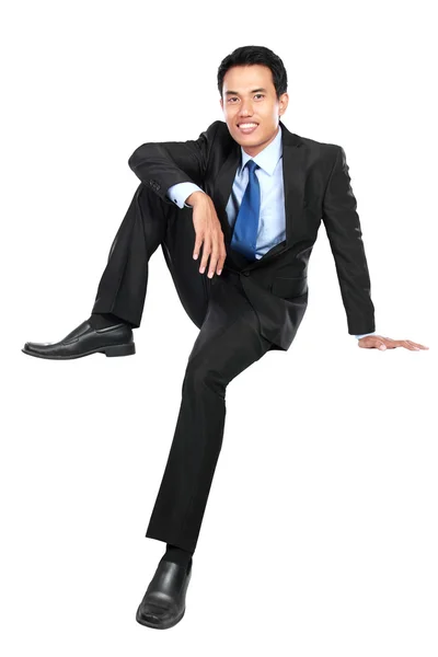 Young businessman smiling and looking at camera while sitting — Stock Photo, Image