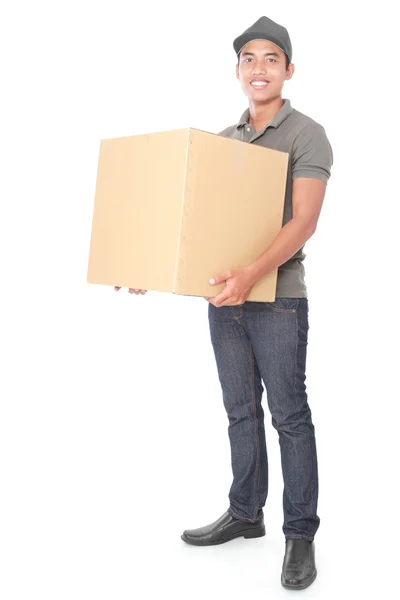 Sorrindo jovem entregador segurando uma caixa de papelão — Fotografia de Stock