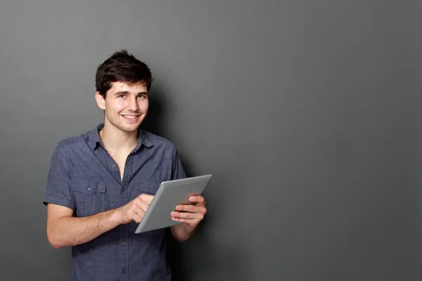 Jeune mâle souriant à l'aide d'une tablette numérique — Photo