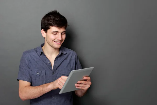 Молодий чоловік посміхається за допомогою цифрового планшета — стокове фото