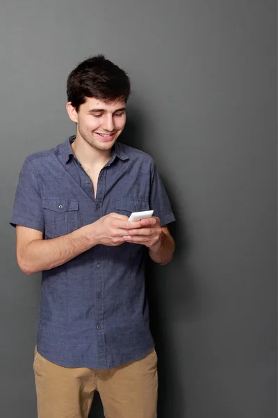 Молодой мужчина улыбается с помощью мобильного телефона — стоковое фото