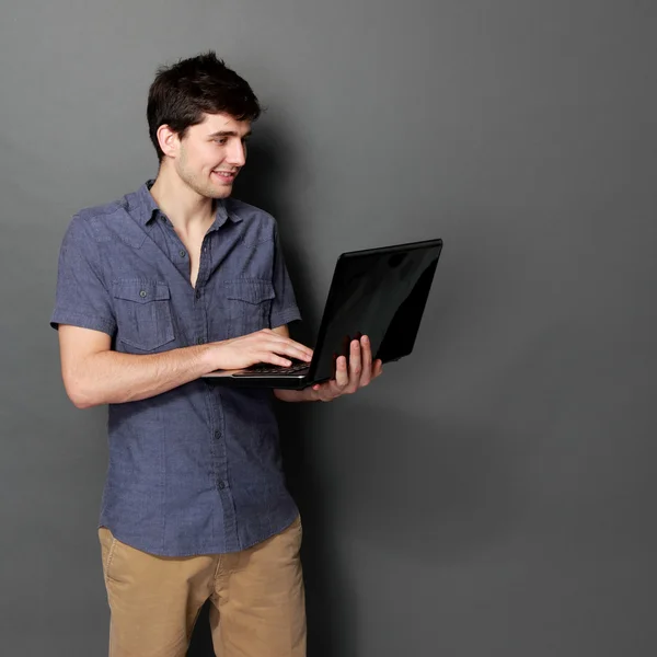 Joven macho sonriendo usando ordenador portátil —  Fotos de Stock