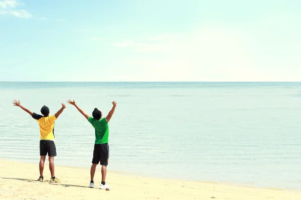 Dois homens levantaram o braço na praia — Fotografia de Stock