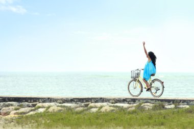 Woman having fun riding bicycle at the beach