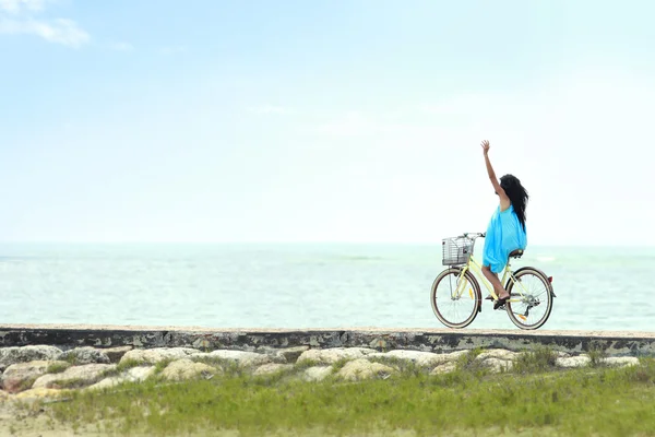 Mujer divirtiéndose montando bicicleta en la playa — Foto de Stock