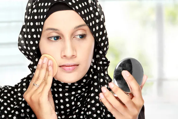 woman with cotton pad applying face powder