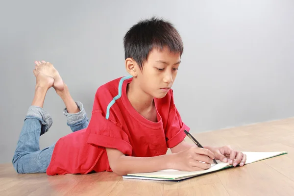 Kleiner Junge schreibt auf den Boden — Stockfoto