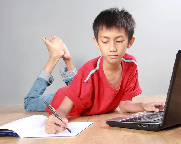 Niño estudiando con libros y portátil —  Fotos de Stock