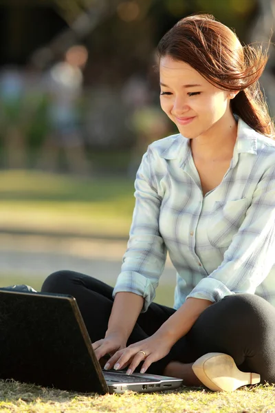 Dizüstü bilgisayar ve kitap ile oturan kız — Stok fotoğraf