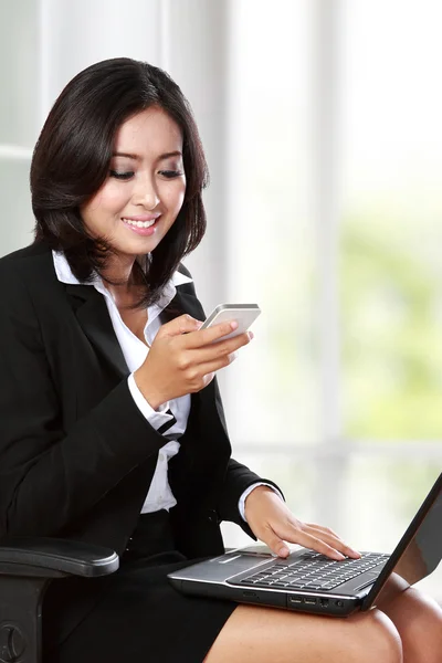 Jonge zakenvrouw mobiele telefoon gebruiken terwijl u werkt in het kantoor — Stockfoto