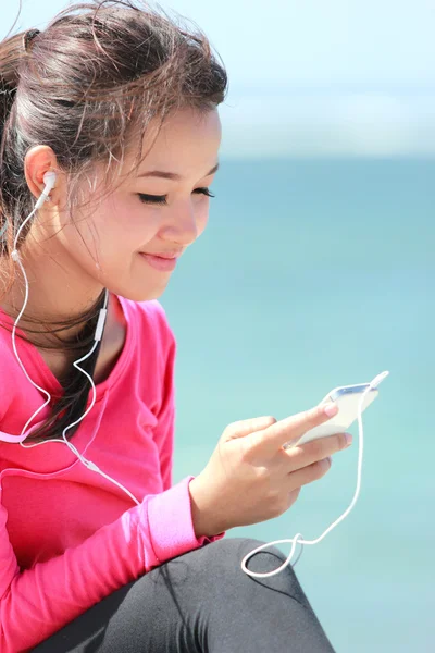 Sportieve jonge vrouw met behulp van mobiele telefoon — Stockfoto