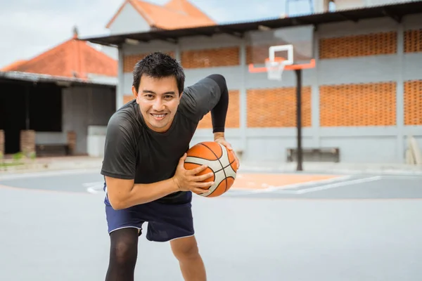 Баскетболіст тримає баскетбол в позі, що тримає м'яч під час дриблінгу — стокове фото