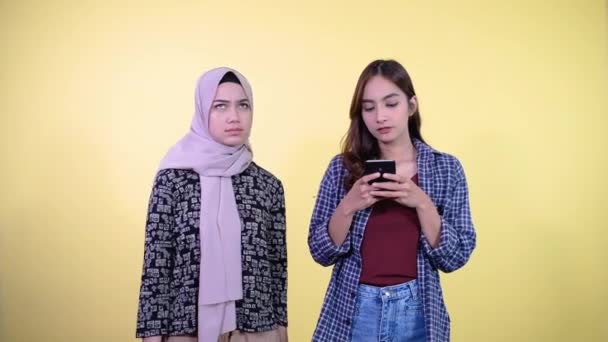 Kvinde ved hjælp af en mobiltelefon og en kvinde ved siden af hende ser mistænkeligt – Stock-video