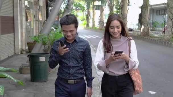 Asiatico uomo e donna su loro telefono parlare mentre andando per ufficio — Video Stock