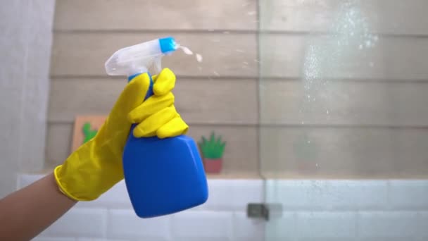 Primer plano de pulverización de las manos con un pulverizador de botella al limpiar el vidrio — Vídeo de stock