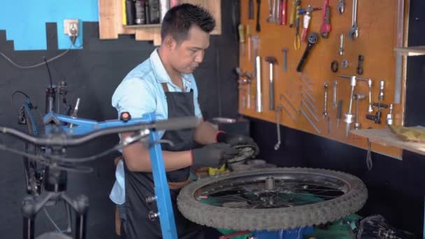 Un mécanicien de vélo dans un tablier portant des gants installe une roue libre — Video