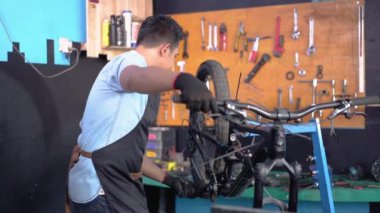 Bisiklet pedalları takılırken eldiven takan önlüklü bir bisiklet tamircisi