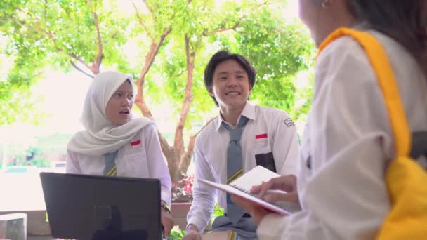 Grupo estudantes do ensino médio usando um computador portátil e carregando livros — Vídeo de Stock